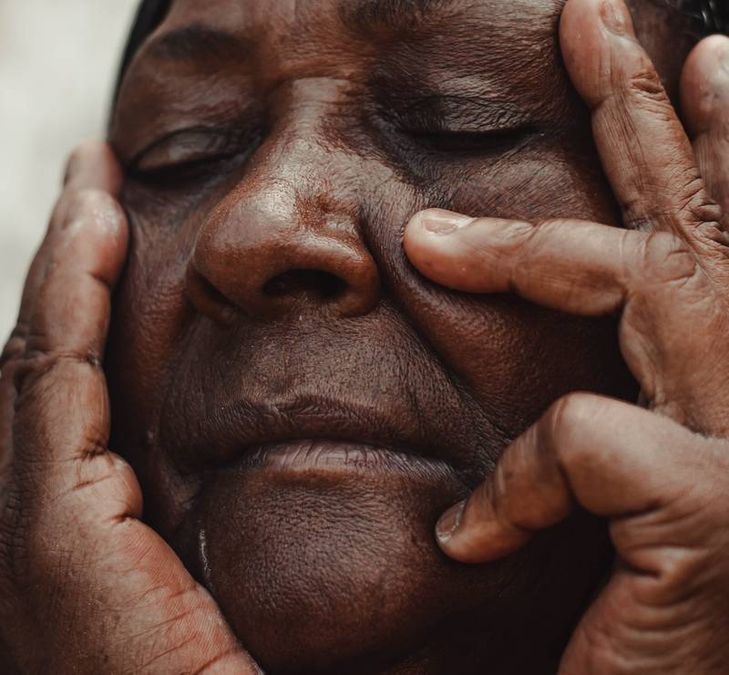 bien-comprendre-la-peau-noire Femme noire, avec une peau marquée par le temps. Elle caresse son propre visage, les yeux fermés et les traits délicats – Cabinet du Docteur Dominique DENJEAN à PARIS 2
